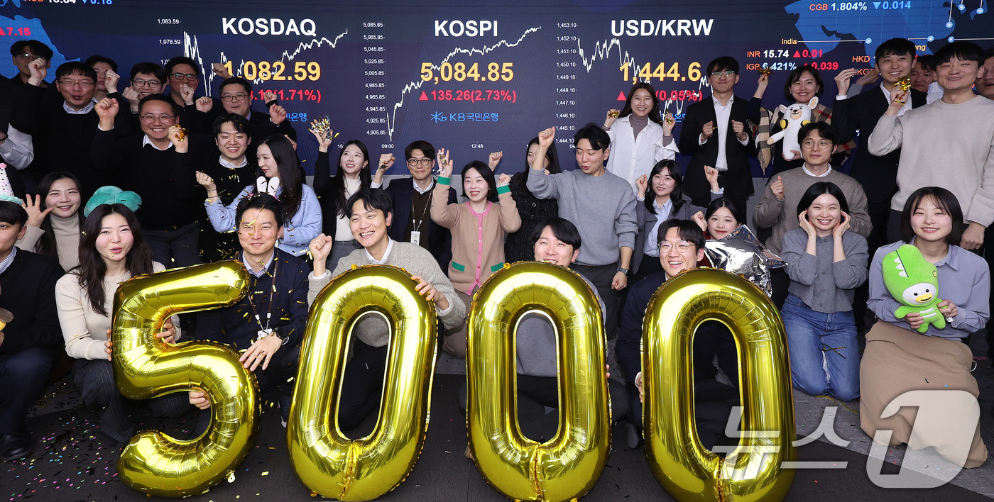 (서울=뉴스1) 박지혜 기자 = 코스피가 종가 기준 사상 처음 5000선을 돌파한 27일 오후 서울 영등포구 KB국민은행 딜링룸에서 직원들이 축하 세리머니를 하고 있다.이날 코스피 …