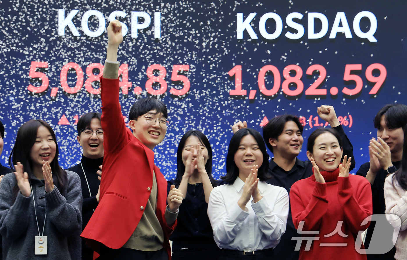 (서울=뉴스1) 이호윤 기자 = 한국 증시 최초로 종가 기준 코스피 5000을 달성한 27일 서울 영등포구 한국거래소에서 직원들이 코스피 종가가 표시된 전광판을 배경으로 세레머니를 …
