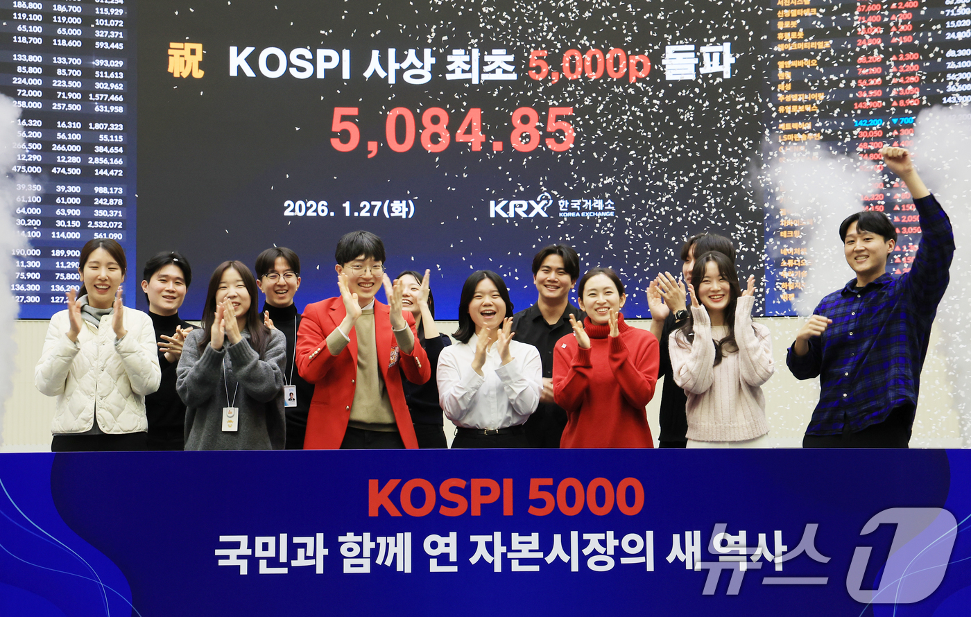 (서울=뉴스1) 이호윤 기자 = 한국 증시 최초로 종가 기준 코스피 5000을 달성한 27일 서울 영등포구 한국거래소에서 직원들이 코스피 종가가 표시된 전광판을 배경으로 세레머니를 …