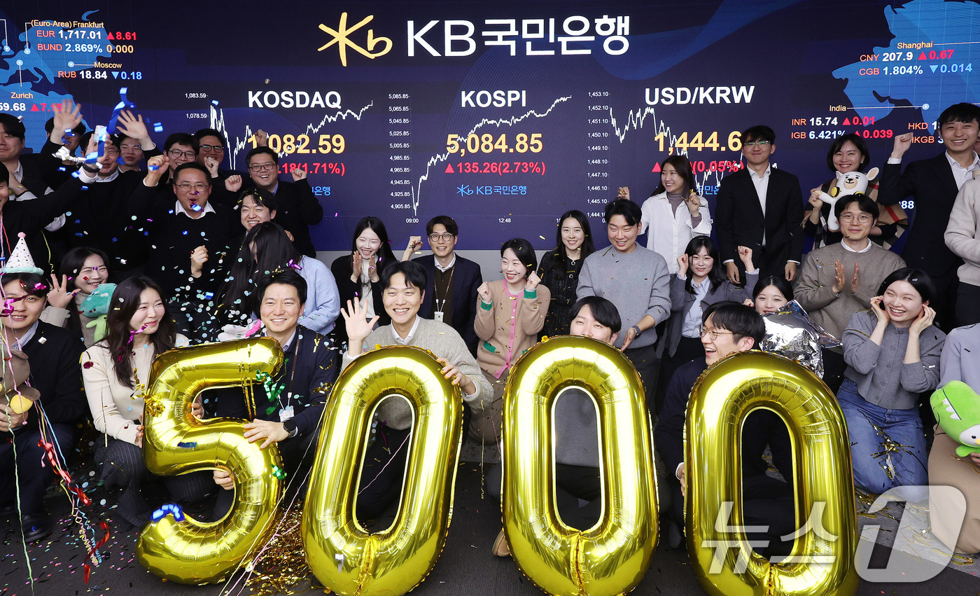 (서울=뉴스1) 박지혜 기자 = 코스피가 종가 기준 사상 처음 5000선을 돌파한 27일 오후 서울 영등포구 KB국민은행 딜링룸에서 직원들이 축하 세리머니를 하고 있다.이날 코스피 …