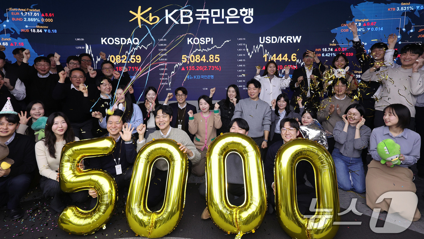 (서울=뉴스1) 박지혜 기자 = 코스피가 종가 기준 사상 처음 5000선을 돌파한 27일 오후 서울 영등포구 KB국민은행 딜링룸에서 직원들이 축하 세리머니를 하고 있다.이날 코스피 …