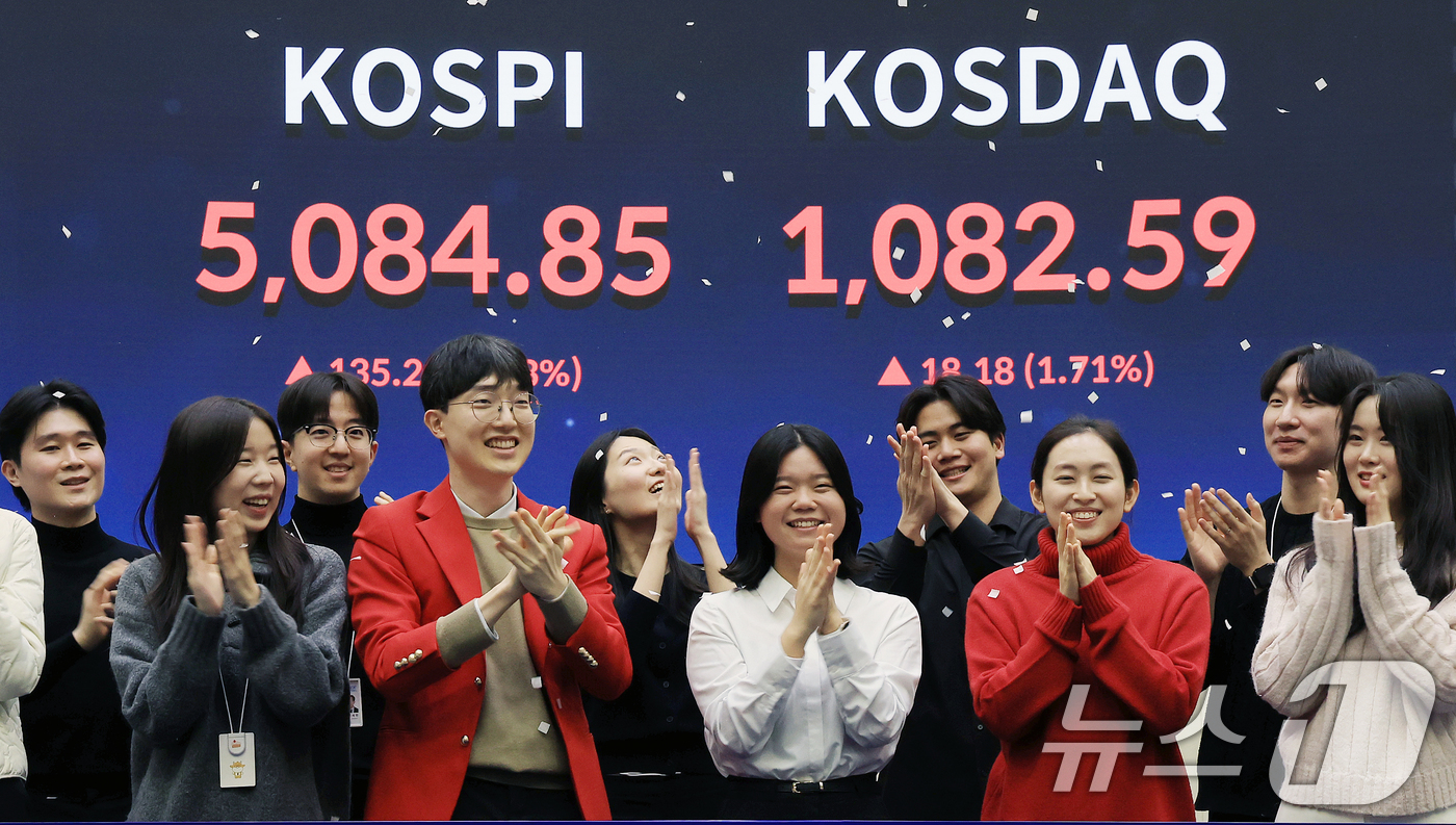 (서울=뉴스1) 이호윤 기자 = 한국 증시 최초로 종가 기준 코스피 5000을 달성한 27일 서울 영등포구 한국거래소에서 직원들이 코스피 종가가 표시된 전광판을 배경으로 세레머니를 …