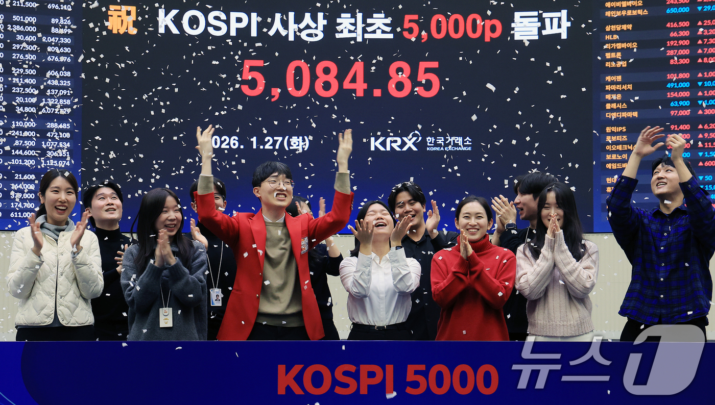 (서울=뉴스1) 이호윤 기자 = 한국 증시 최초로 종가 기준 코스피 5000을 달성한 27일 서울 영등포구 한국거래소에서 직원들이 코스피 종가가 표시된 전광판을 배경으로 세레머니를 …