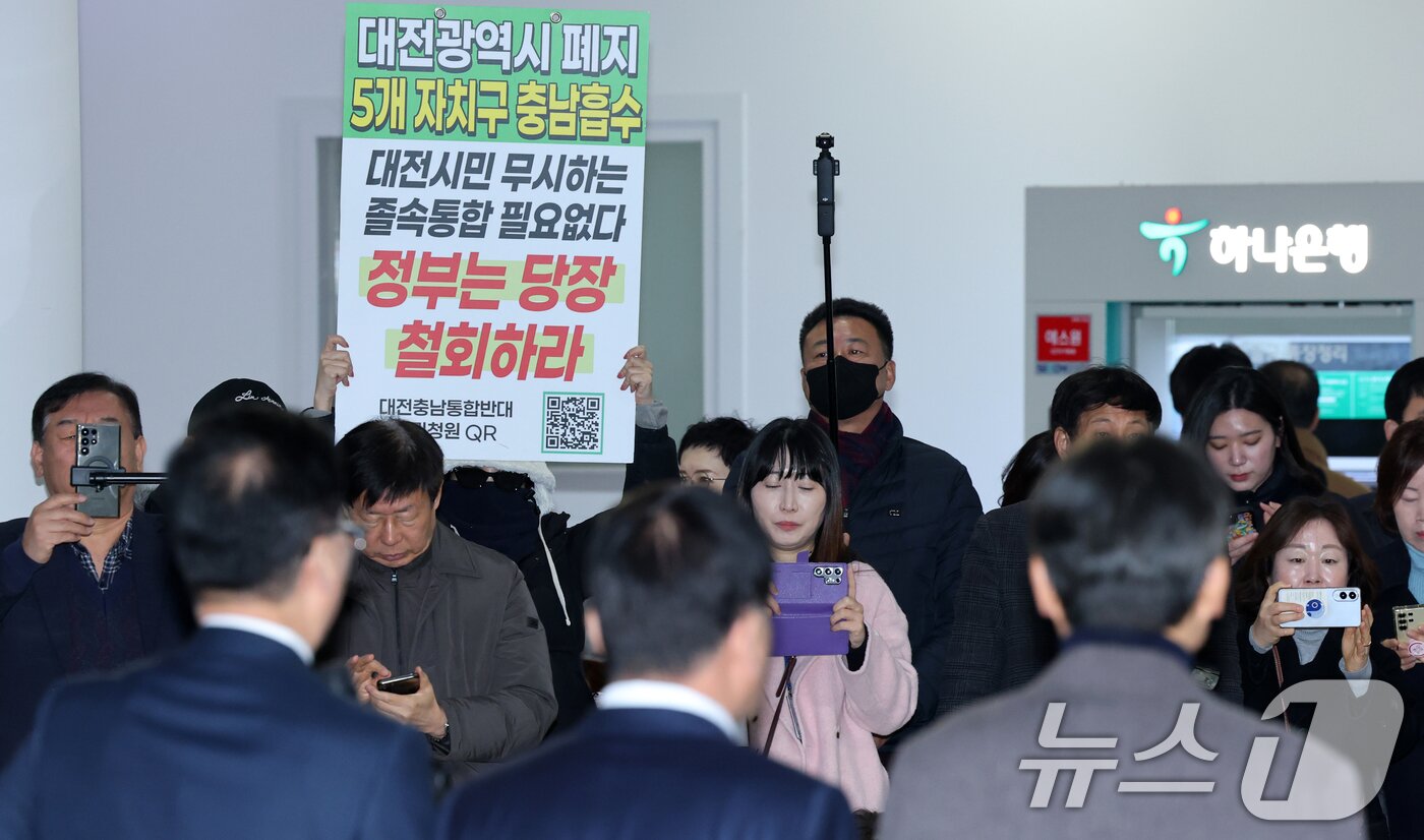 본문 이미지 - 조원휘 대전시의회 의장과 홍성현 충남도의회 의장이 29일 대전시의회에서 대전·충남 행정통합 관련 공동 기자회견중 시민단체가 통합반대 피켓을 들고 있다. 2026.1.29/뉴스1 ⓒ News1 김기태 기자