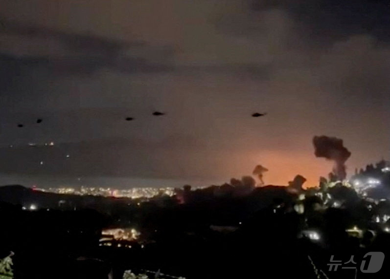 (로이터=뉴스1) 김성진 기자 = 3일(현지시간) 베네수엘라 수도 카라카스 상공에서 헬기들이 폭발로 인해 피어오르는 연기 기둥을 지나쳐 비행하고 있다. 2025.1.3ⓒ 로이터=뉴 …