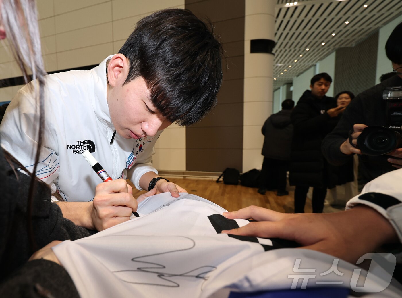 본문 이미지 - 2026 밀라노·코르티나담페초 동계올림픽에 출전하는 대한민국 스피드스케이팅 대표팀의 정재원이 30일 오전 인천국제공항 제2터미널을 통해 이탈리아 밀라노로 출국 전 응원 온 팬이 가져온 태극기에 사인을 하고 있다. 2026.1.30/뉴스1 ⓒ News1 김진환 기자