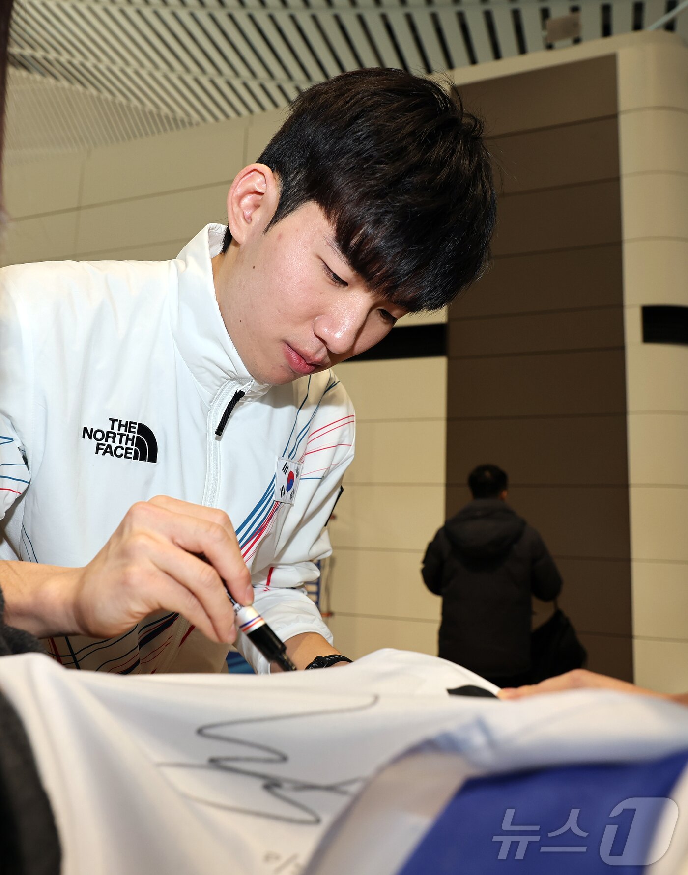 본문 이미지 - 2026 밀라노·코르티나담페초 동계올림픽에 출전하는 대한민국 스피드스케이팅 대표팀의 정재원이 30일 오전 인천국제공항 제2터미널을 통해 이탈리아 밀라노로 출국 전 응원 온 팬이 가져온 태극기에 사인을 하고 있다. 2026.1.30/뉴스1 ⓒ News1 김진환 기자