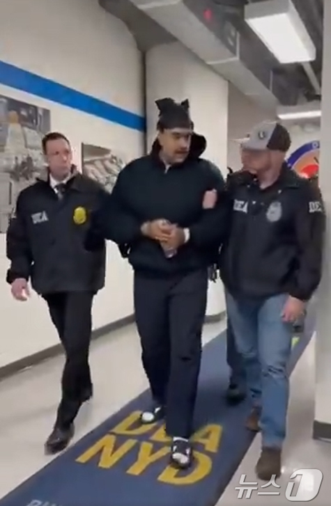 (서울=뉴스1) = 니콜라스 마두로 베네수엘라 대통령이 3일(현지시간) 미국 마약단속국(DEA) 요원에게 이끌려 '퍼프 워크'(perp walk·수사기관이 피의자를 언론 카메라에 …