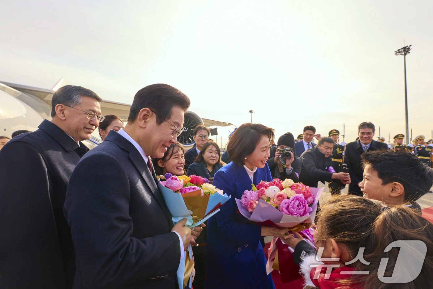(베이징(중국)=뉴스1) 허경 기자 = 중국을 국빈방문하는 이재명 대통령과 김혜경 여사가 4일 베이징 서우두 공항에서 화동들에게 꽃다발을 전달 받고 있다. (공동취재) 2026.1 …