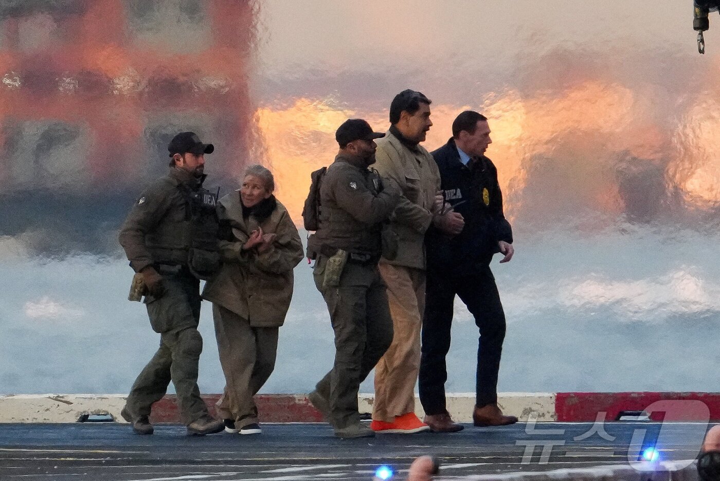 본문 이미지 - 니콜라스 마두로 베네수엘라 대통령과 부인 실리아 플로레스가 5일(현지시간) 미국 뉴욕 맨해튼에 도착한 헬기에서 내려 마약단속국(DEA) 요원들에 의해 연방 법원으로 호송되고 있다. 2026.1.5 ⓒ 로이터=뉴스1