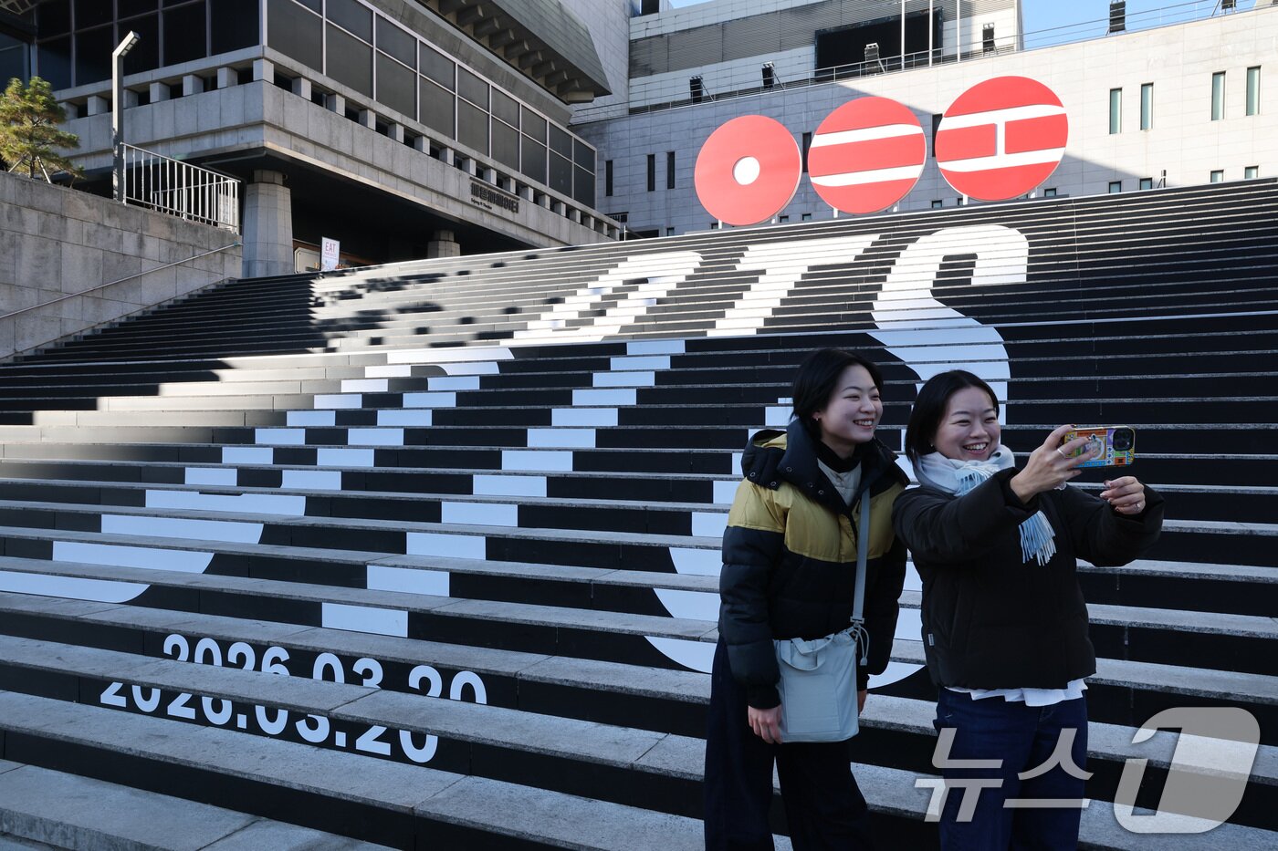 본문 이미지 - 6일 오전 서울 종로구 세종문화회관 야외 계단에 설치된 BTS(방탄소년단)의 컴백 로고 조형물 앞에서 관광객들이 기념촬영을 하고 있다.  2026.1.6/뉴스1 ⓒ News1 임세영 기자