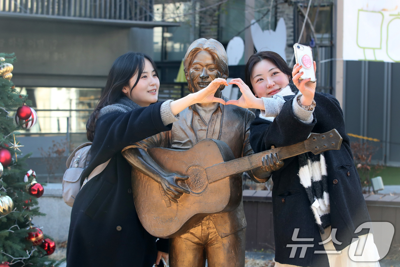 (대구=뉴스1) 공정식 기자 = '영원한 가객' 故 김광석(1964∼1996) 30주기인 6일 오후 대구 중구 방천시장 김광석길을 찾은 시민들이 김광석 동상 옆에서 기념촬영을 하고 …