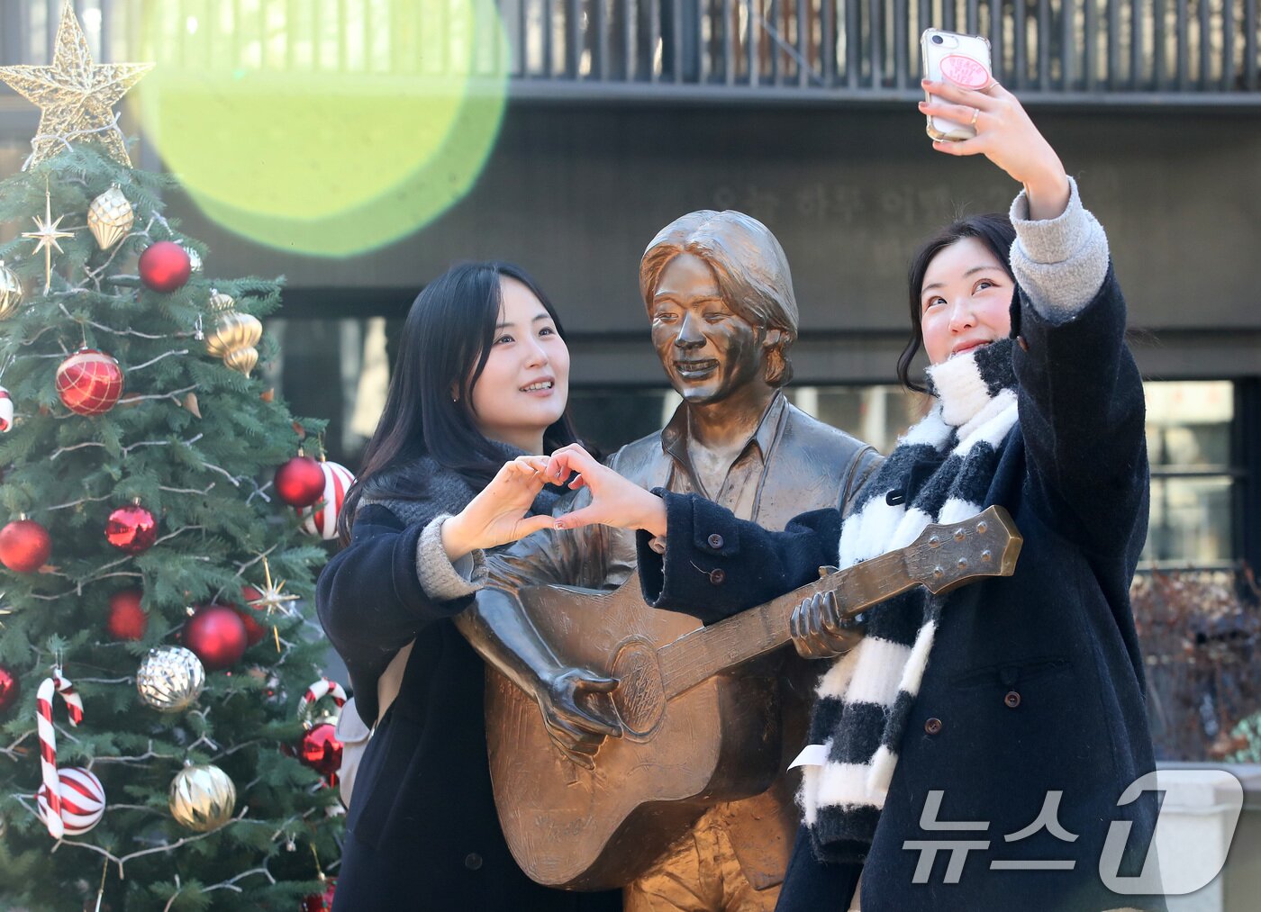 본문 이미지 - '영원한 가객' 고(故) 김광석(1964∼1996) 30주기인 6일 오후 대구 중구 방천시장 김광석길을 찾은 시민들이 김광석 동상 옆에서 기념촬영을 하고 있다. 2026.1.6/뉴스1 ⓒ News1 공정식 기자