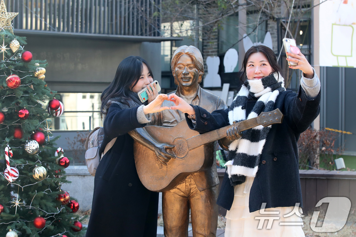 (대구=뉴스1) 공정식 기자 = '영원한 가객' 故 김광석(1964∼1996) 30주기인 6일 오후 대구 중구 방천시장 김광석길을 찾은 시민들이 김광석 동상 옆에서 기념촬영을 하고 …