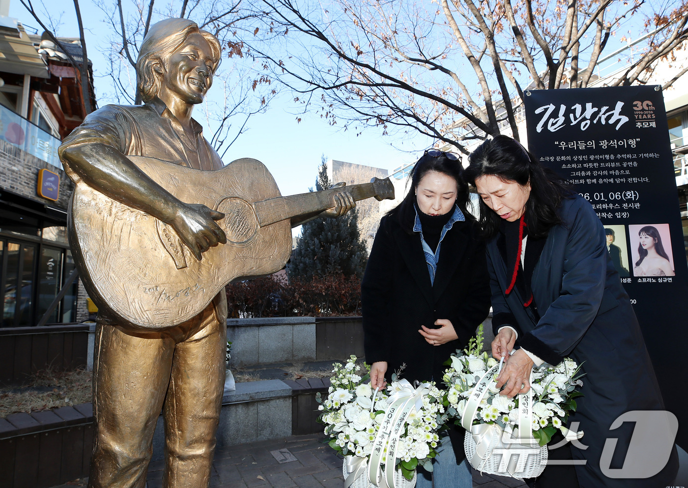 (대구=뉴스1) 공정식 기자 = '영원한 가객' 故 김광석(1964∼1996) 30주기인 6일 오후 대구 중구 방천시장 김광석길을 찾은 시민들이 김광석 동상에 꽃다발을 내려놓고 있 …