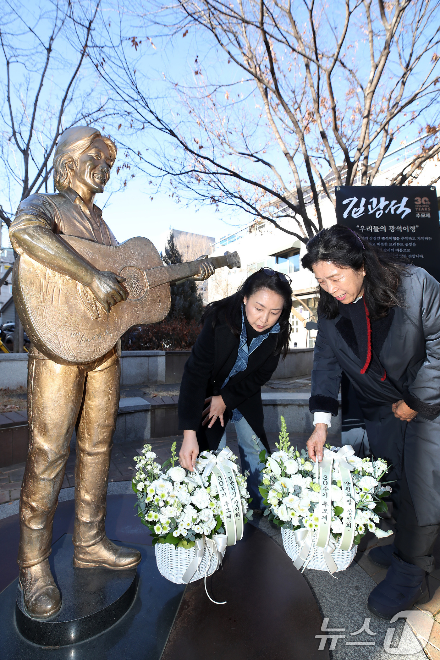 (대구=뉴스1) 공정식 기자 = '영원한 가객' 故 김광석(1964∼1996) 30주기인 6일 오후 대구 중구 방천시장 김광석길을 찾은 시민들이 김광석 동상에 꽃다발을 내려놓고 있 …