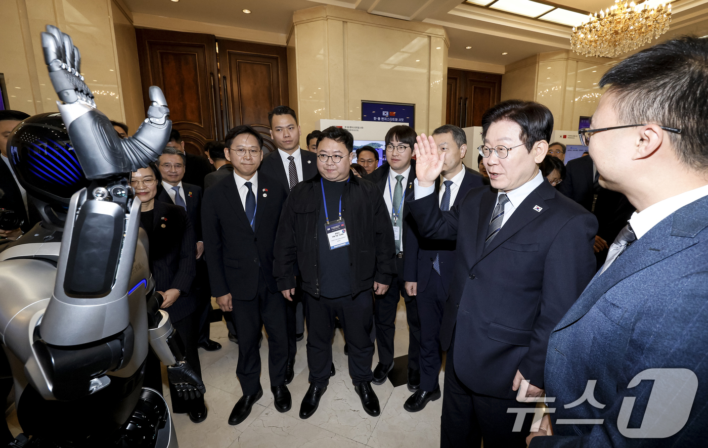 (상하이(중국)=뉴스1) 허경 기자 = 이재명 대통령이 7일 중국 상하이 국제회의중심에서 열린 한중 벤처스타트업 서밋 행사에서 중국 기업 엣지봇의 휴머노이드 로봇을 살펴보고 있다. …