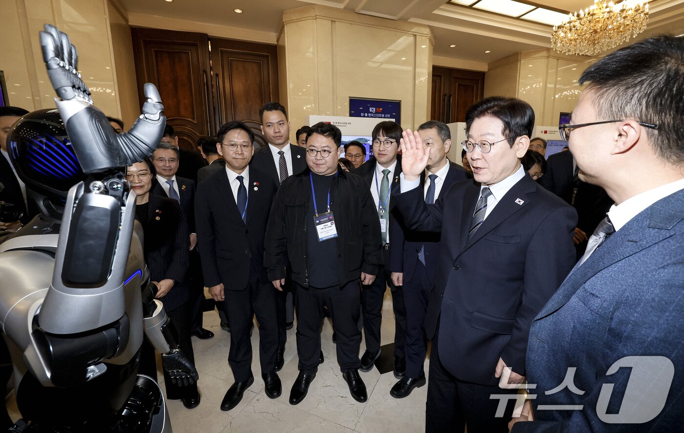 본문 이미지 - 이재명 대통령이 7일 중국 상하이 국제회의중심에서 열린 한중 벤처스타트업 서밋 행사에서 중국 기업 엣지봇의 휴머노이드 로봇을 살펴보고 있다. 2026.1.7/뉴스1 ⓒ News1 허경 기자