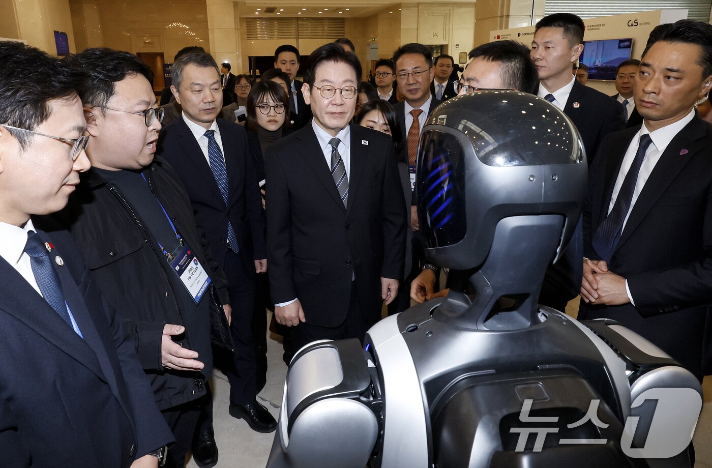 본문 이미지 - 이재명 대통령이 7일 중국 상하이 국제회의중심에서 열린 한중 벤처스타트업 서밋 행사에서 중국 기업 엣지봇의 휴머노이드 로봇을 살펴보고 있다. 2026.1.7/뉴스1 ⓒ News1 허경 기자