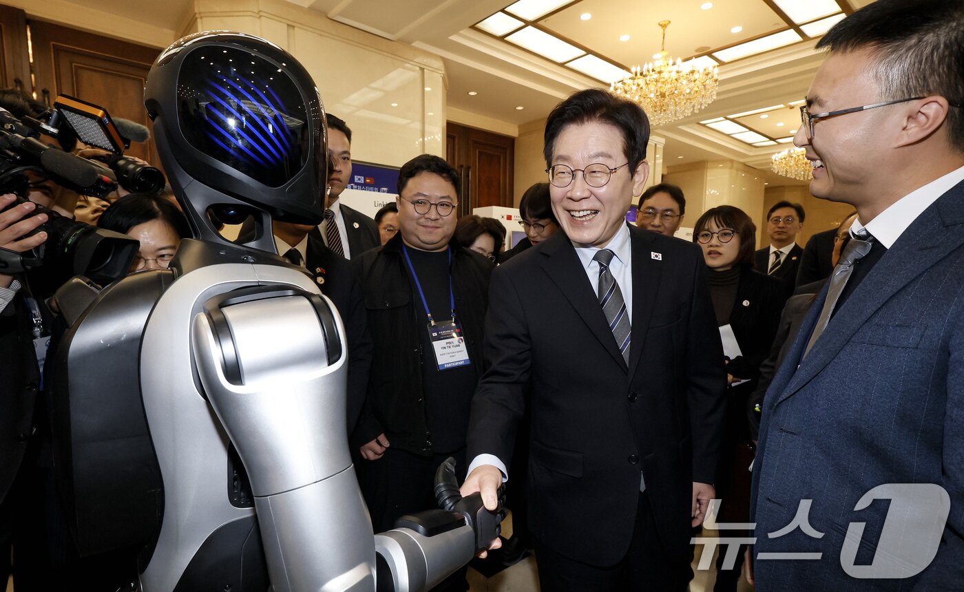 본문 이미지 - 이재명 대통령이 7일 중국 상하이 국제회의중심에서 열린 한중 벤처스타트업 서밋 행사에서 중국 기업 엣지봇의 휴머노이드 로봇을 살펴보고 있다. 2026.1.7/뉴스1 ⓒ News1 허경 기자