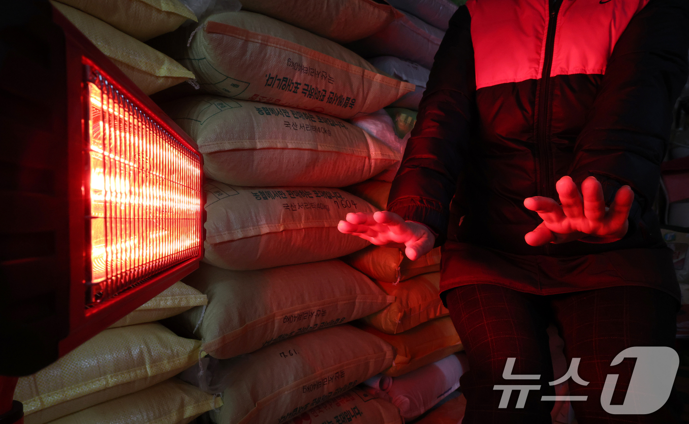 (수원=뉴스1) 김영운 기자 = 전국 대부분 지역에 영하권 추위를 보인 8일 경기 수원시 팔달구 미나리광시장에서 상인들이 전기난로에 몸을 녹이고 있다. 2026.1.8/뉴스1