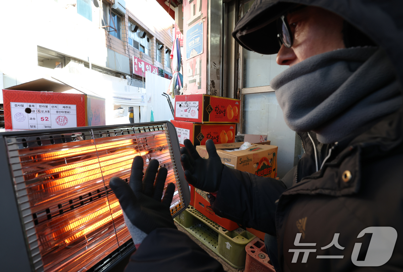 (수원=뉴스1) 김영운 기자 = 전국 대부분 지역에 영하권 추위를 보인 8일 경기 수원시 팔달구 영동시장에서 상인들이 전기난로에 몸을 녹이고 있다. 2026.1.8/뉴스1