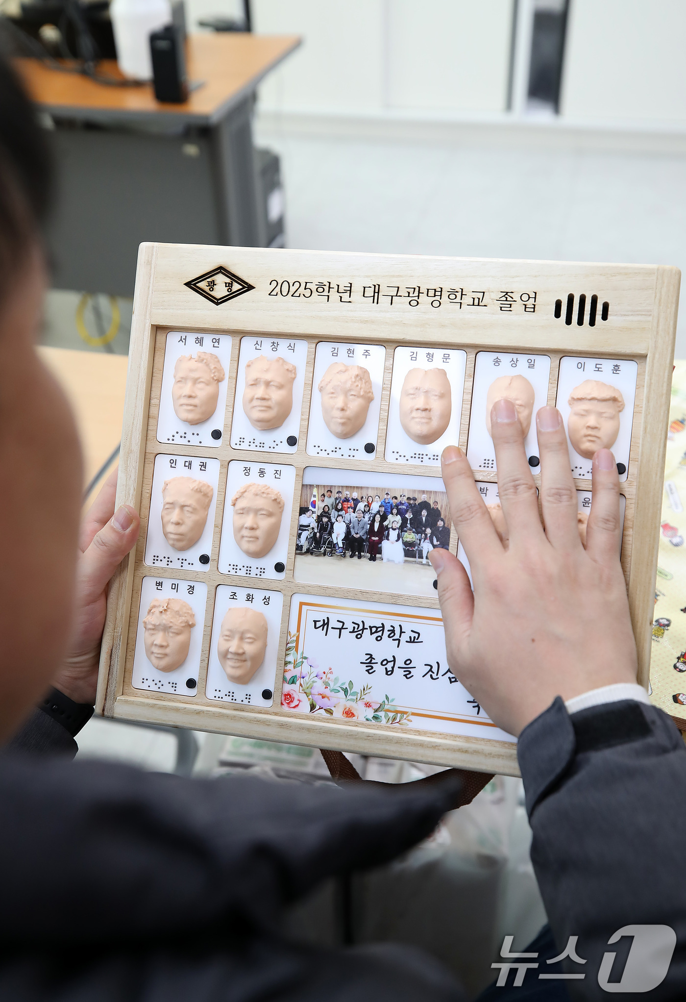(대구=뉴스1) 공정식 기자 = 8일 오전 대구 남구 대명동 시각장애인 교육기관 대구광명학교의 2025학년도 졸업식에서 3D 프린터로 제작된 졸업앨범을 받은 졸업생이 친구들의 얼굴 …