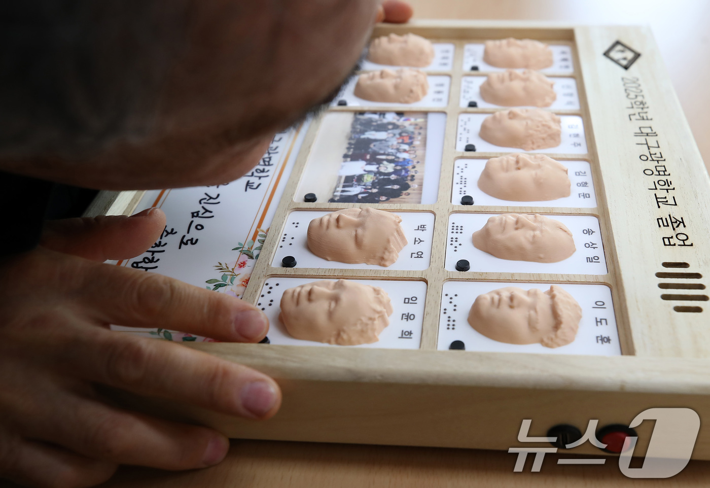 (대구=뉴스1) 공정식 기자 = 8일 오전 대구 남구 대명동 시각장애인 교육기관 대구광명학교의 2025학년도 졸업식에서 3D 프린터로 제작된 졸업앨범을 받은 졸업생이 친구들의 얼굴 …