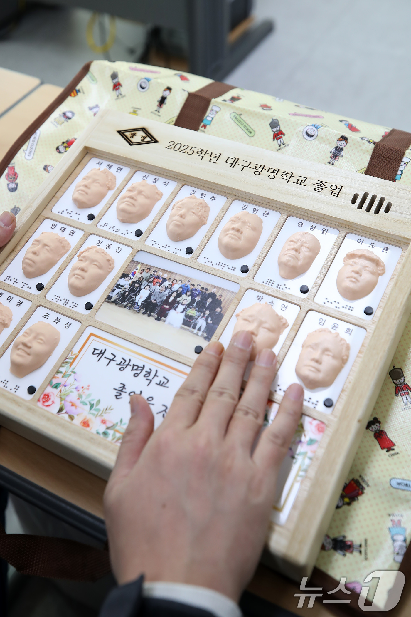 (대구=뉴스1) 공정식 기자 = 8일 오전 대구 남구 대명동 시각장애인 교육기관 대구광명학교의 2025학년도 졸업식에서 3D 프린터로 제작된 졸업앨범을 받은 졸업생이 친구들의 얼굴 …