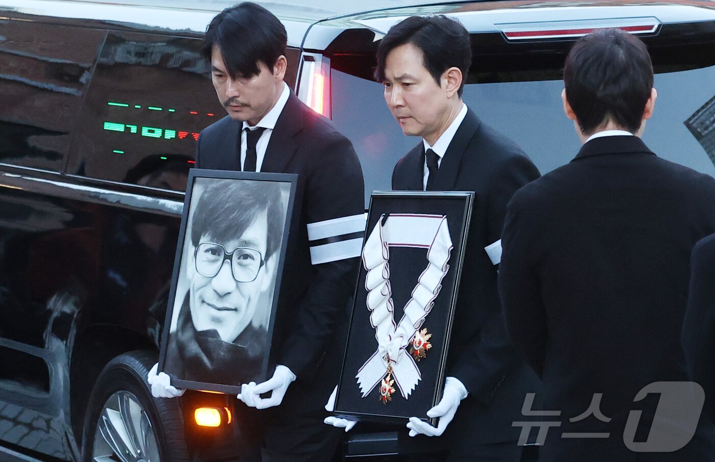 본문 이미지 - 배우 정우성과 이정재가 故 안성기의 장례 미사를 위해 9일 오전 서울 중구 명동성당으로 들어서고 있다. 정우성은 고인의 영정을, 이정재는 금관문화훈장을 들고 있다. 2026.1.9/뉴스1 ⓒ News1 권현진 기자