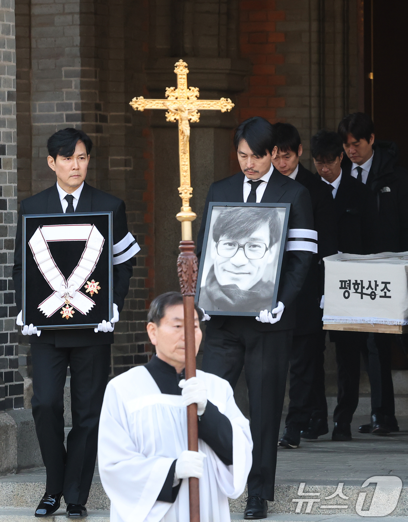 (서울=뉴스1) 권현진 기자 = 배우 이정재와 정우성이 9일 오전 서울 중구 명동성당에서 고 안성기의 장례 미사를 마친 뒤 영결식장으로 향하고 있다. 정우성은 고인의 영정을, 이정 …