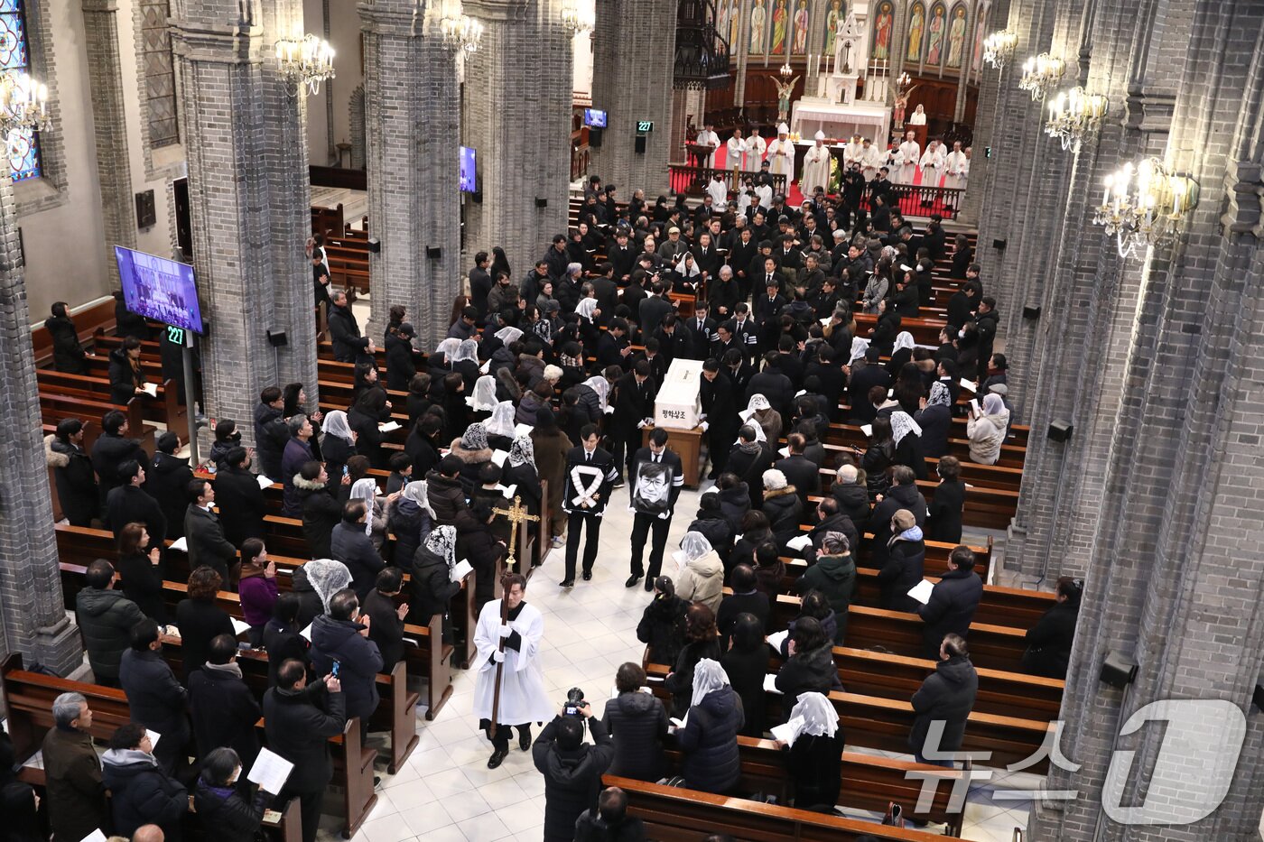 본문 이미지 - 배우 이정재와 정우성이 9일 오전 서울 중구 명동성당에서 고 안성기의 장례 미사를 마친 뒤 영결식장으로 향하고 있다. 정우성은 고인의 영정을, 이정재는 금관문화훈장을 들고 있다. (천주교 서울대교구 제공. 재판매 및 DB 금지) 2026.1.9/뉴스1 ⓒ News1 임세영 기자