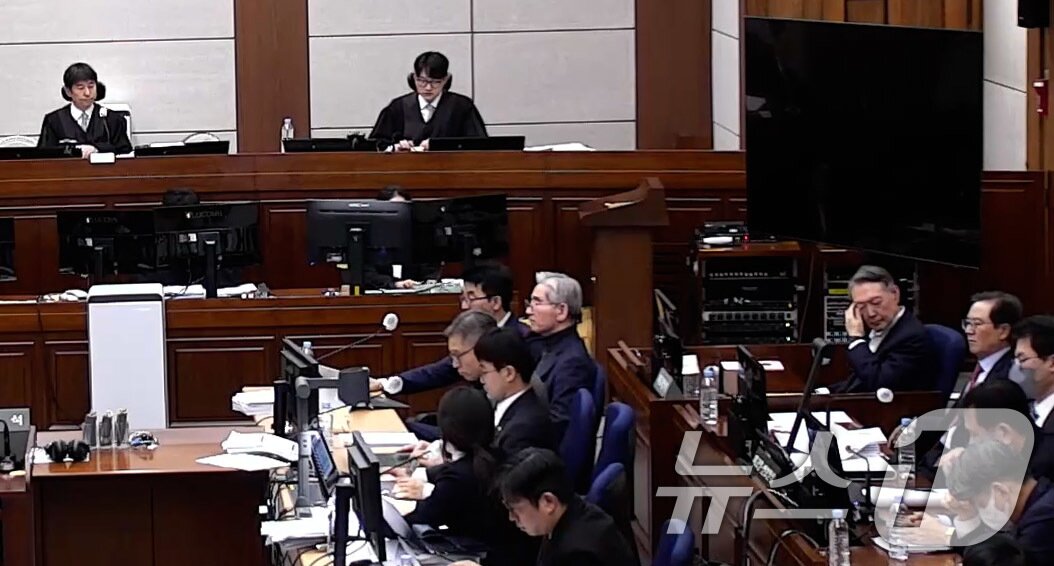 본문 이미지 - 윤석열 전 대통령이 9일 오후 서울 서초구 서울중앙지방법원에서 열린 내란 우두머리 혐의 1심 결심 공판에 출석해 자리에 앉아 생각에 잠겨 있다. 윤 전 대통령 앞에는 김용현 전 국방부 장관이 앉아 있다.(서울중앙지방법원 제공 영상 캡쳐. 재판매 및 DB 금지) 2026.1.9/뉴스1