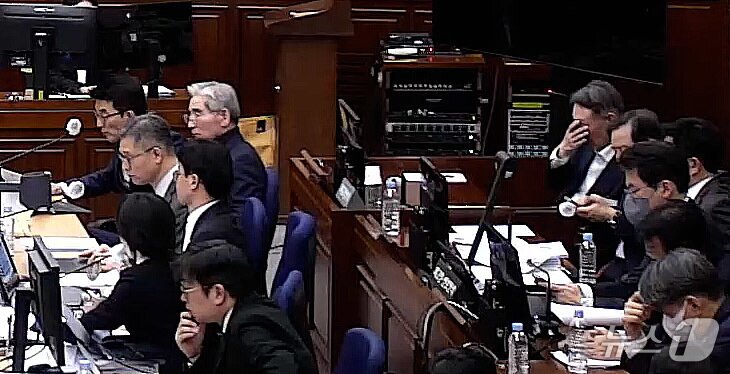 본문 이미지 - 윤석열 전 대통령이 9일 오후 서울 서초구 서울중앙지방법원에서 열린 내란 우두머리 혐의 1심 결심 공판에 출석해 얼굴을 만지고 있다. 윤 전 대통령 앞에는 김용현 전 국방부 장관이 앉아 있다. (서울중앙지방법원 제공 영상 캡쳐. 재판매 및 DB 금지) 2026.1.9/뉴스1