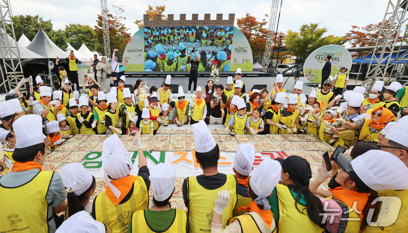 (임실=뉴스1) = 11일 전북 임실군 임실치즈테마파크에서 열린 2026 임실N치즈축제에서 한득수 군수와 정일윤 군의장이 대형쌀피자 만들기에 참여해 관광객들과 치즈를 뿌리는 퍼포먼 …