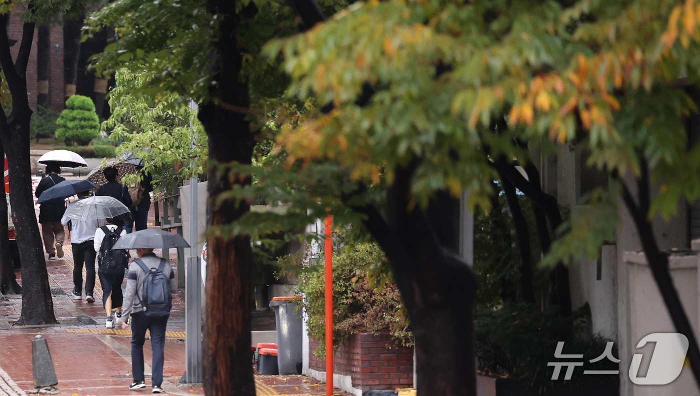 (서울=뉴스1) 이종덕 기자 = 13일 오전 우산을 쓴 시민들이 서울 태평로에서 출근길 발걸음을 재촉하고 있다. 기상청은 오후에 기온이 뚝 떨어지겠다고 예보했다.  2026.10. …