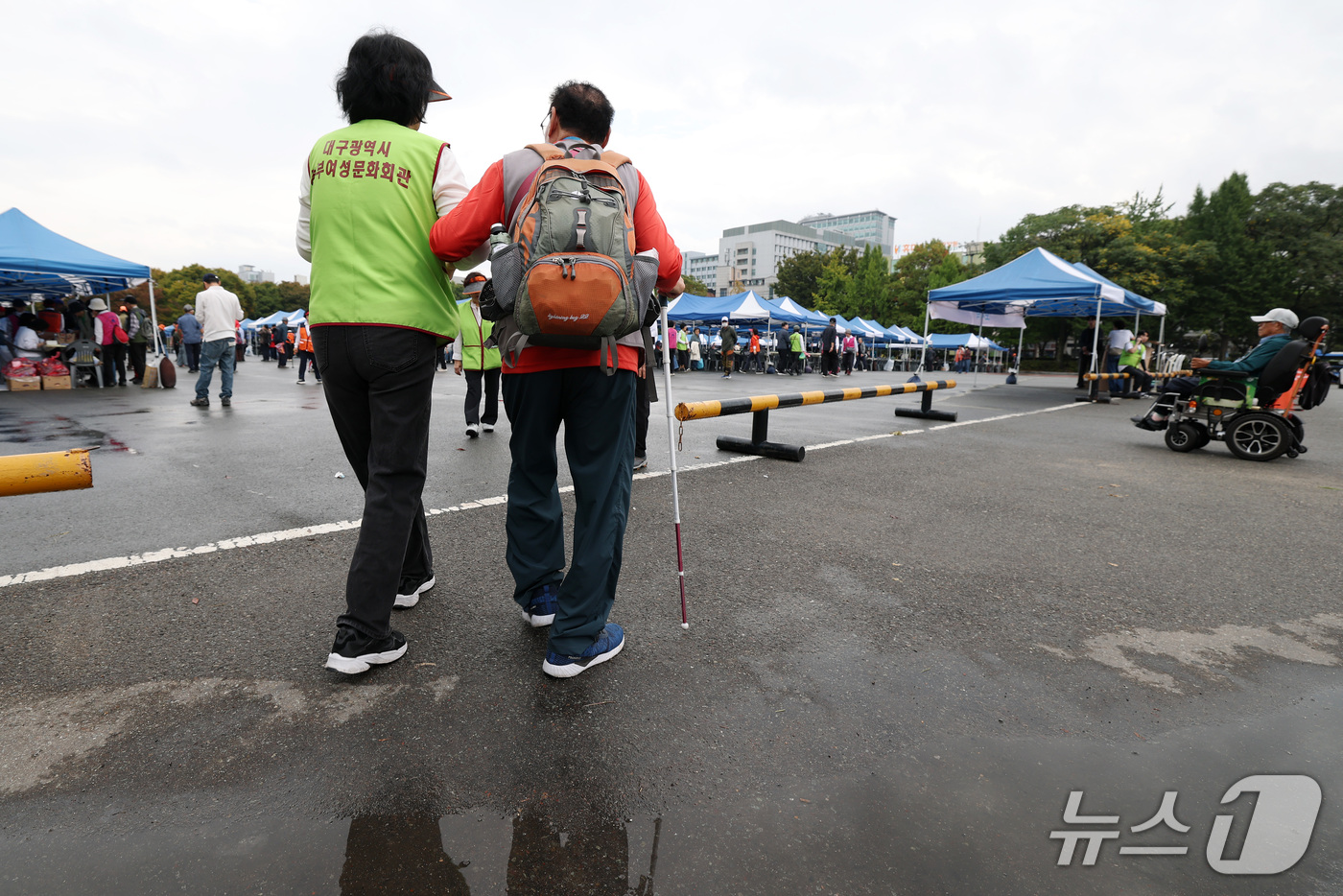 (대구=뉴스1) 공정식 기자 = 13일 대구 달서구 두류공원 인라인스케이트장에서 열린 '제47회 흰지팡이의 날 기념 대구시각장애인복지대회'를 찾은 시각장애인이 자원봉사자의 도움을 …