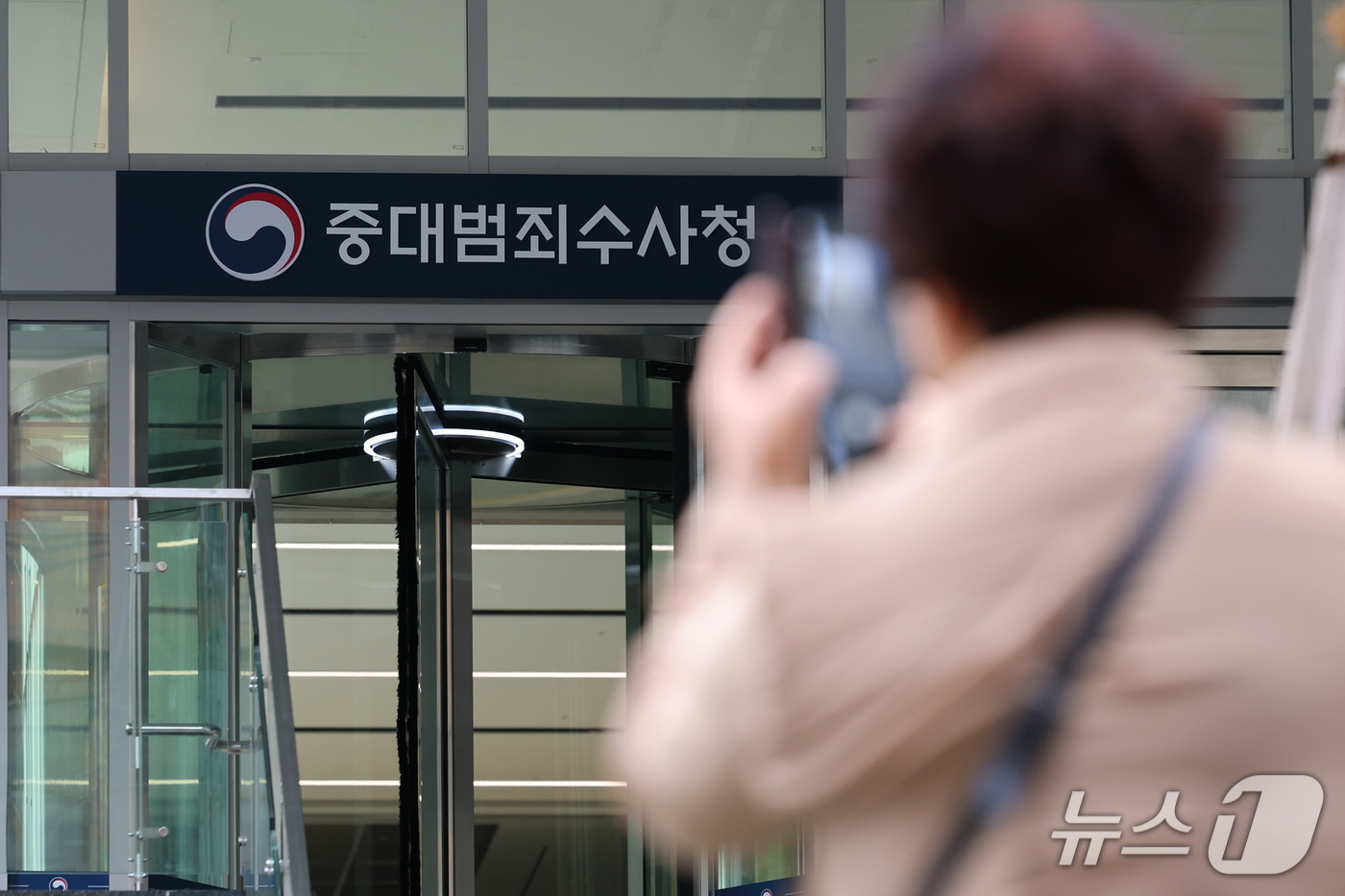 (서울=뉴스1) 안은나 기자 = 13일 서울 중구 중대범죄수사청 앞에서 한 시민이 현판을 촬영하고 있다.정부가 이날 발표한 '2차 중앙행정기관 이전 계획'에 따르면 중수청, 공소청 …