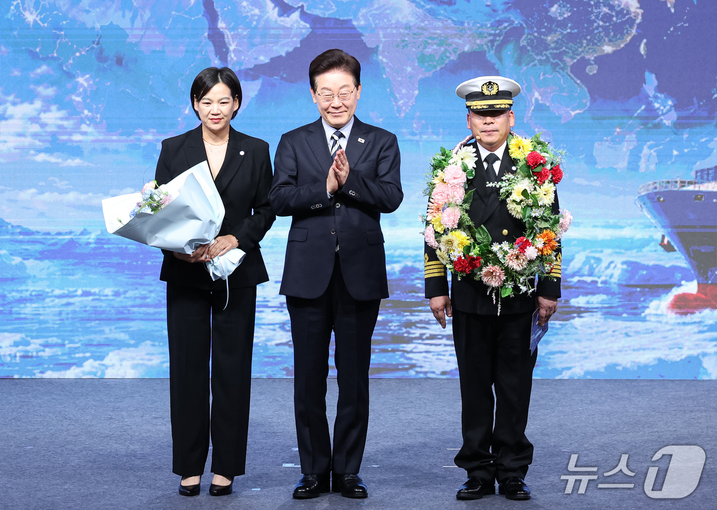(부산=뉴스1) 허경 기자 = 이재명 대통령이 13일 부산에서 열린 북극항로 시범운항 환영식에서 서명원 팬스타 아크로호 선장에게 꽃목걸이를 수여한 후 기념촬영을 하고 있다. 202 …
