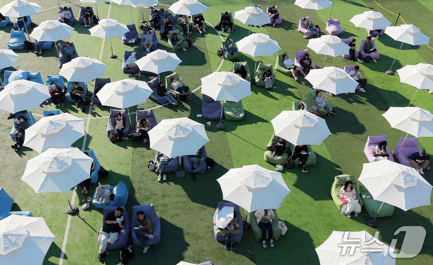 (부산=뉴스1) 윤일지 기자 = 14일 오후 부산 부산진구 동의과학대학교 인조잔디 운동장에서 열린 'Fall in Books' 야외도서관 행사에 참가한 학생들이 독서를 하고 있다. …