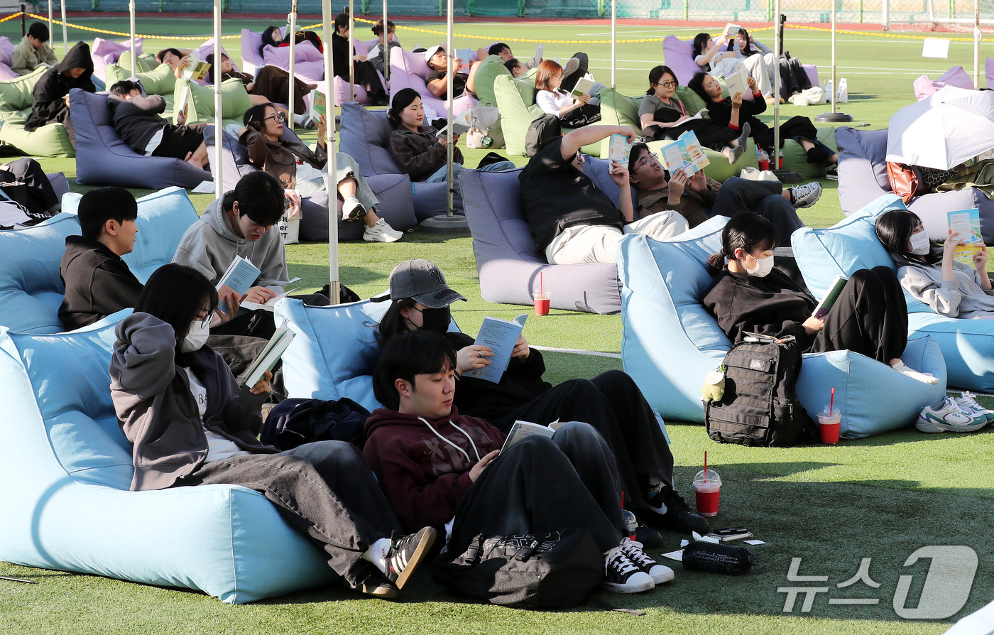 (부산=뉴스1) 윤일지 기자 = 14일 오후 부산 부산진구 동의과학대학교 인조잔디 운동장에서 열린 'Fall in Books' 야외도서관 행사에 참가한 학생들이 독서를 하고 있다. …
