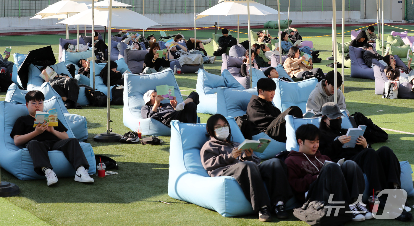 (부산=뉴스1) 윤일지 기자 = 14일 오후 부산 부산진구 동의과학대학교 인조잔디 운동장에서 열린 'Fall in Books' 야외도서관 행사에 참가한 학생들이 독서를 하고 있다. …