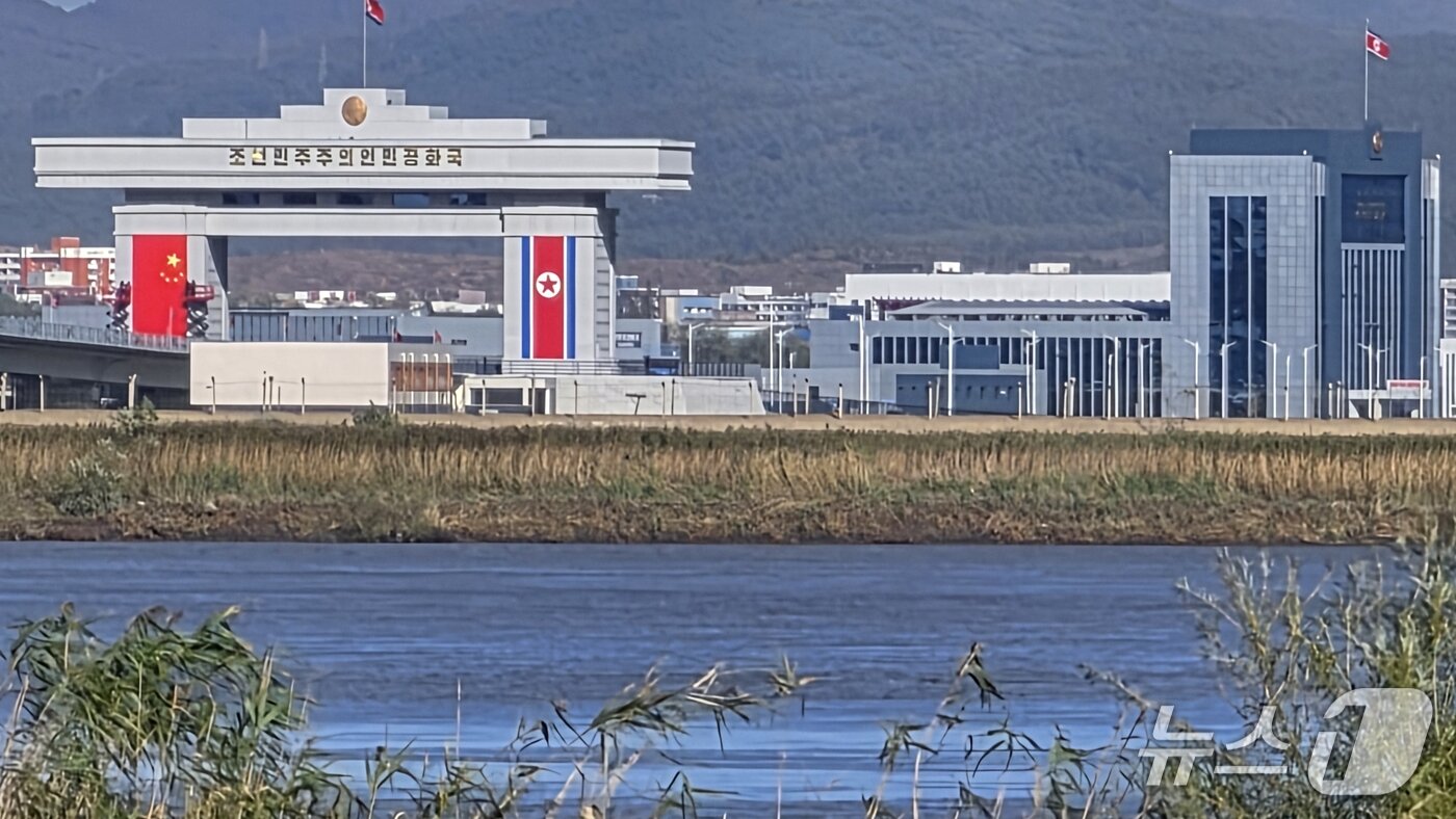 본문 이미지 - 신압록강대교 정식 개통을 하루 앞둔 14일 중국 랴오닝성 단둥에서 바라본 대교 북한 쪽 관문 양쪽 기둥부에 중국 오성홍기와 북한 인공기가 나란히 걸려 있다. 2026.10.14. ⓒ 단둥=뉴스1 노민호 특파원