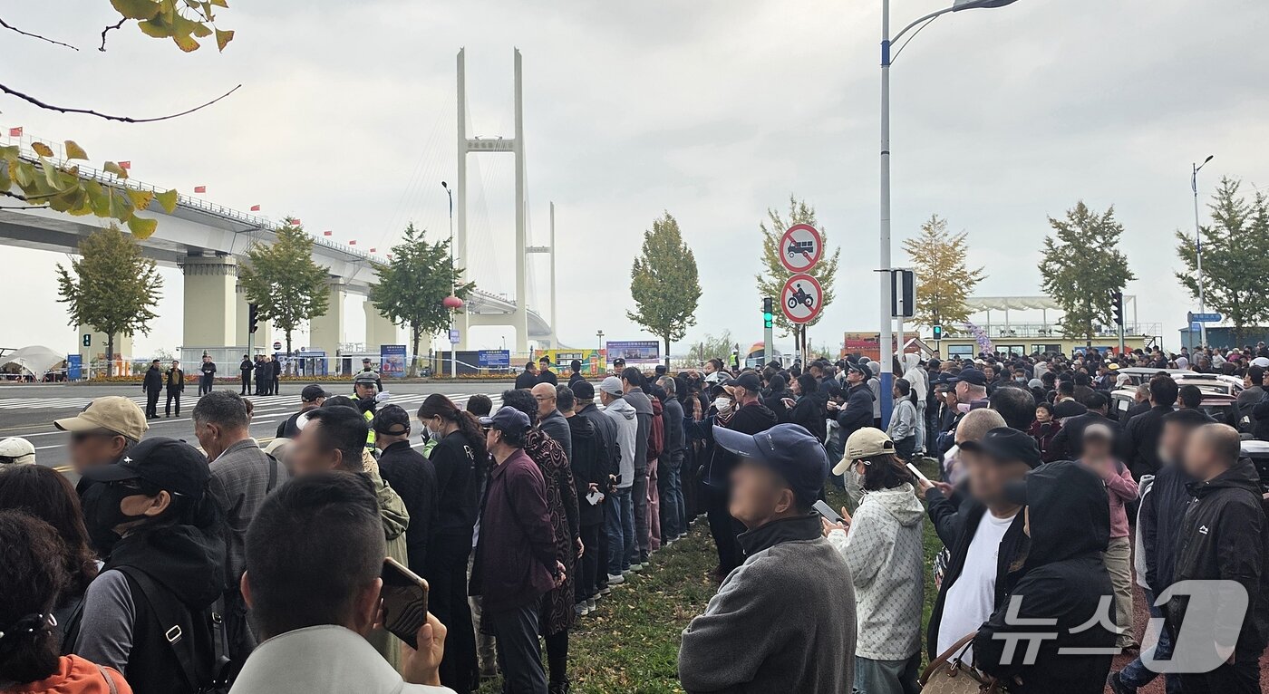 본문 이미지 - 15일 중국 랴오닝성 단둥에서 신압록강대교 정식 개통식이 열린 가운데, 시민들이 공안의 통제 아래 대교 인근에 모여 개통식을 기다리고 있다. 2026.10.15 ⓒ 뉴스1 노민호 특파원