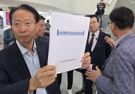 5·18 희생자 명단 기재된 자료 들어보이는 오월단체 회원