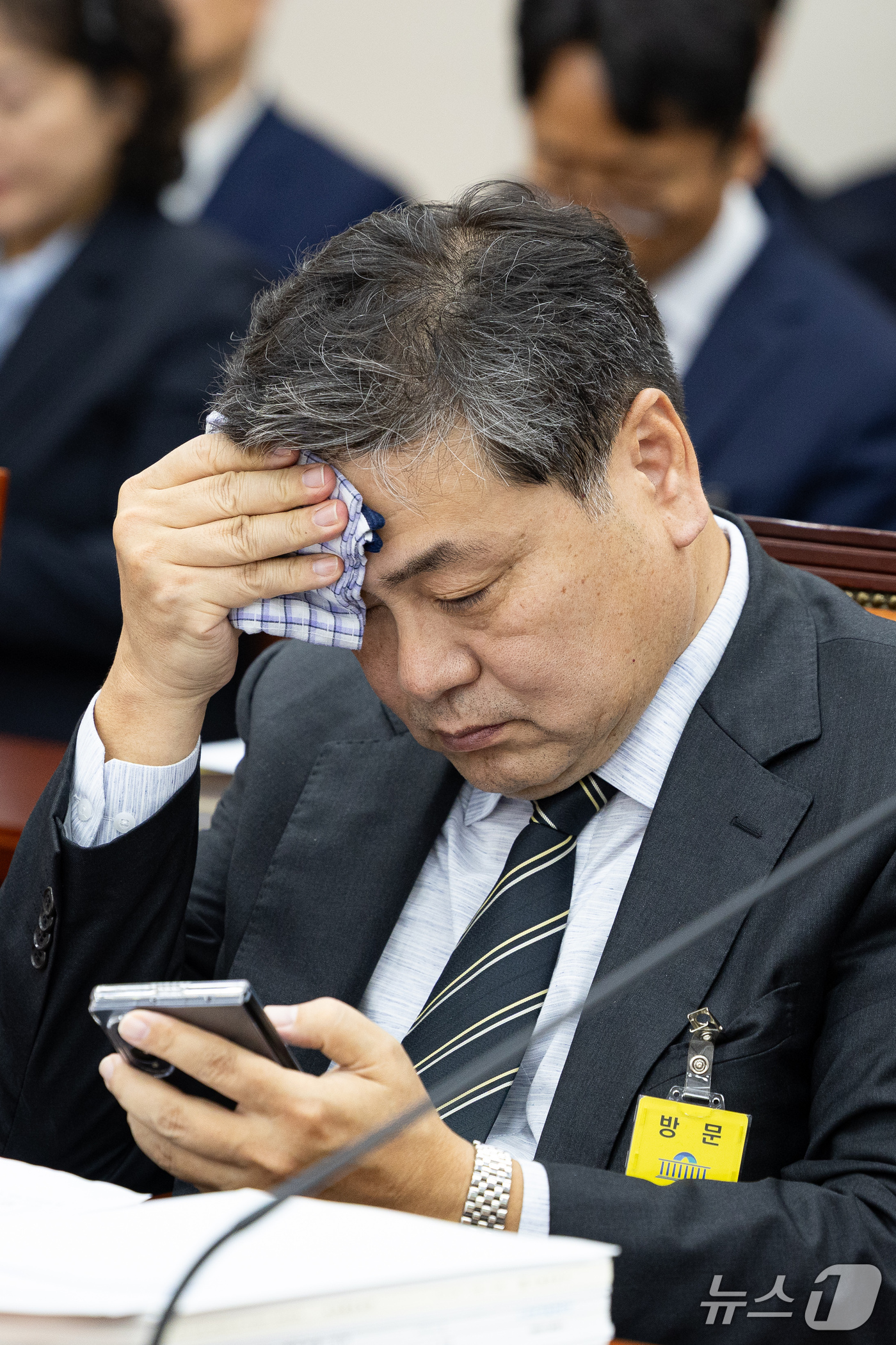 (서울=뉴스1) 유승관 기자 = 이인재 인천대학교 총장이 16일 서울 여의도 국회에서 열린 교육위원회의 서울대학교 등에 대한 국정감사에 출석해 땀을 닦으며 휴대전화를 바라보고 있다 …