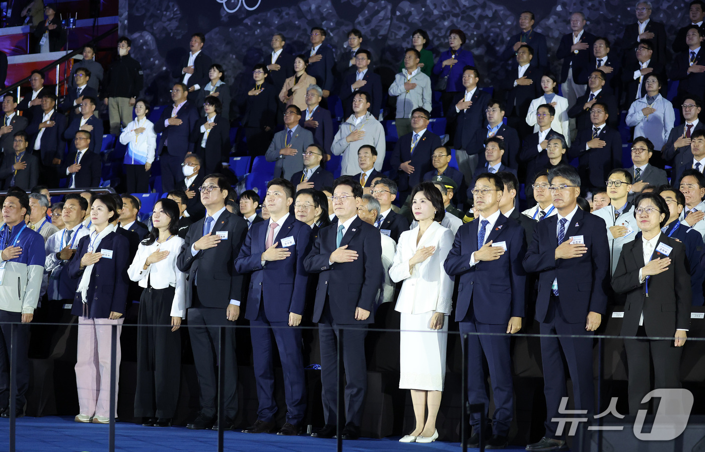 (제주=뉴스1) 이재명 기자 = 이재명 대통령과 김혜경 여사가 16일 제주 서귀포시 제주월드컵경기장에서 열린 제107회 전국체육대회 개회식에서 참석자들과 함께 국기에 경례하고 있다 …