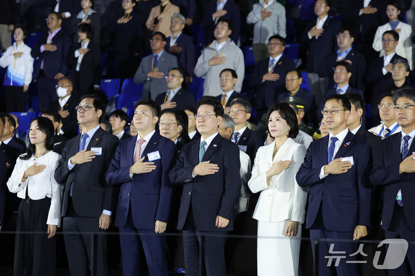 (제주=뉴스1) 이재명 기자 = 이재명 대통령과 김혜경 여사가 16일 제주 서귀포시 제주월드컵경기장에서 열린 제107회 전국체육대회 개회식에서 참석자들과 함께 국기에 경례하고 있다 …