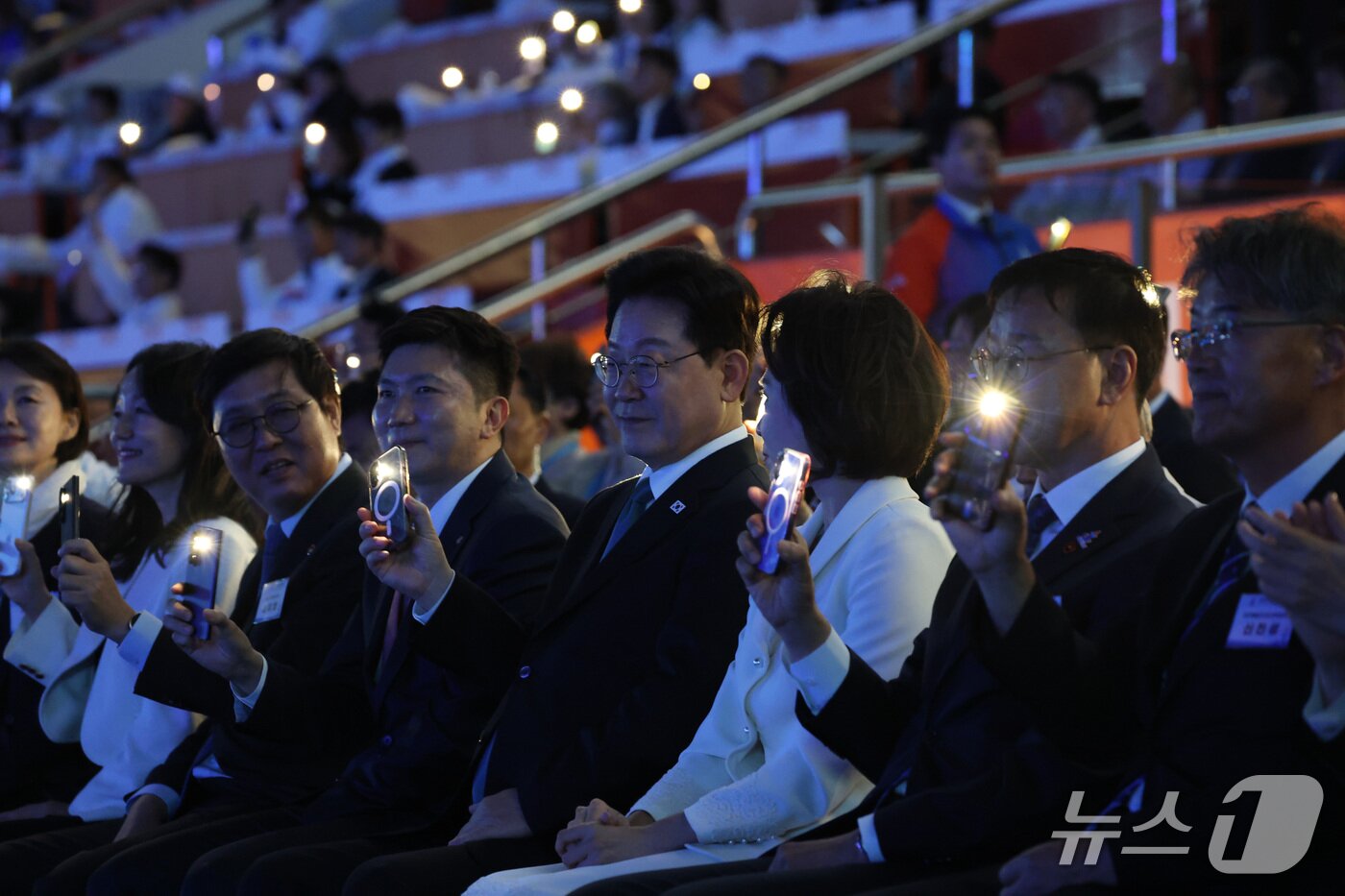 본문 이미지 - 이재명 대통령이 16일 제주 서귀포시 제주월드컵경기장에서 열린 제107회 전국체육대회 개회식에서 휴대전화 조명을 흔들며 성화 봉송을 지켜보고 있다. 2026.10.16 ⓒ 뉴스1 이재명 기자