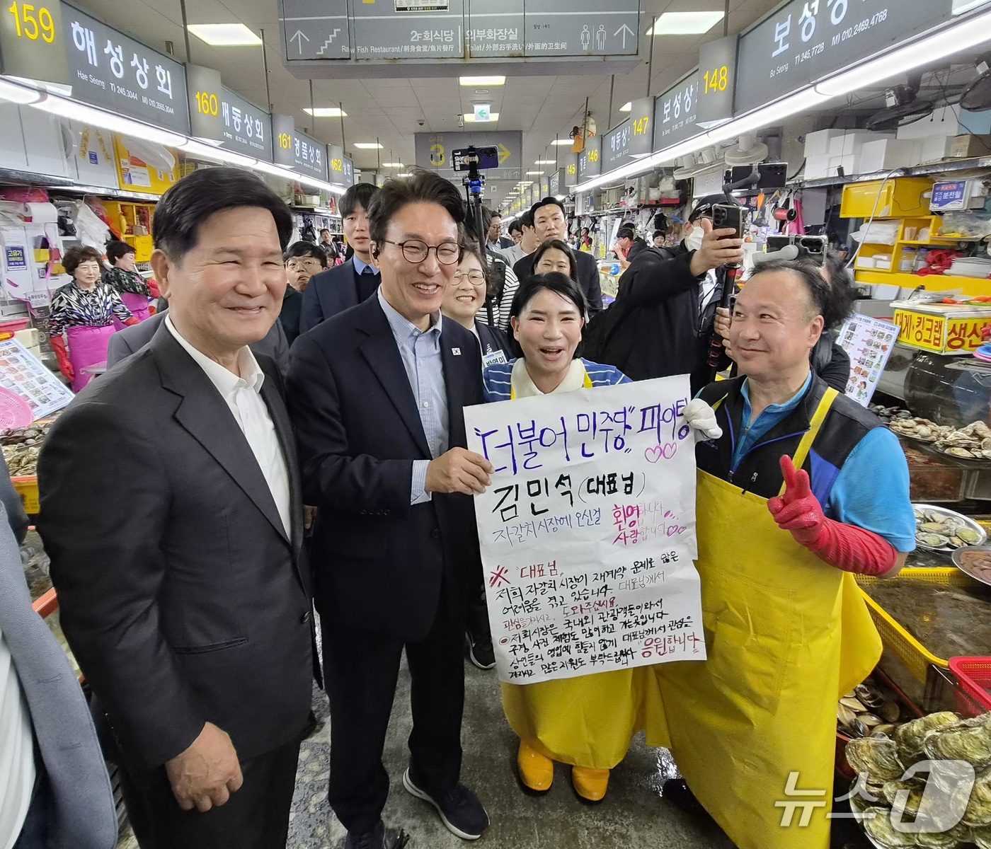(부산=뉴스1) 임순택 기자 = 김민석 더불어민주당 대표가 17일 부산 자갈치시장을 방문해 상인들로부터 현장의 어려움과 응원의 메시지가 적힌 피켓을 전달받고 기념 촬영을 하고 있다 …